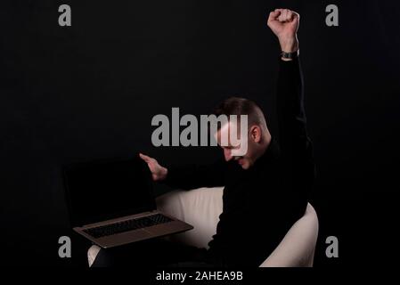 Ich gewann. Gewinnen Erfolg glücklich feiern Sein ein Sieger mit Laptop. Dynamisches Bild der kaukasischen männliches Modell Studio auf schwarzem Hintergrund. Sieg, de Stockfoto