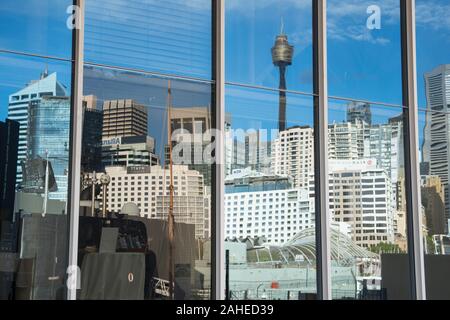 Reflexion der Sydney Tower hoch unter den skyscrappers in Darling Harbour auf die Glasscheiben eines Gebäudes über den Hafen. Stockfoto