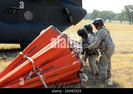 Eine CH-47 Chinook Hubschrauber Crew bereiten eine Antenne Wasser Lieferung Eimer, als "Bambi Bucket' zur Befestigung an einem Flaschenzug Kabel auf das Flugzeug in der Nähe von Falmouth, Texas, Sept. 6, 2011 bekannt. Texas National Guard Mannschaften gestartet aus dem Austin Army Aviation Service Waldbrände bedrohen Häuser und Eigentum zu kämpfen. Der CH-47 Chinook Hubschrauber vom 2-149 Th, TXARNG, wird die Ladeschaufel anheben und die Schaufel in einen See, Teich oder Fluss auf die Schaufel schnell füllen und das Wasser nehmen, Dip, in diesem Fall, auf Brände in der Nähe von Falmouth, Texas, Sept. 6, 2011 fallengelassen zu werden. Texas National Guard Mannschaften gestartet, o Stockfoto