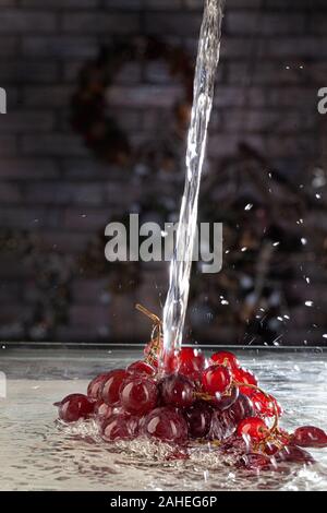 Weintraube und Strom von Wasser auf ein Studio Hintergrund Stockfoto