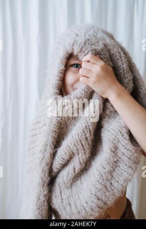 Kleine Mädchen spielen mit Pullover, sie zog ihn über den Kopf, spähen aus der Bohrung Stockfoto