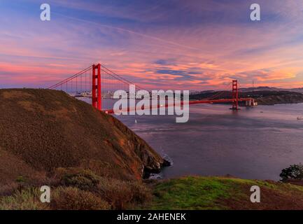 Panorama von der Golden Gate Bridge bei Sonnenuntergang mit Marin Headlands im Vordergrund, San Francisco Skyline und bunten Wolken im Hintergrund Stockfoto