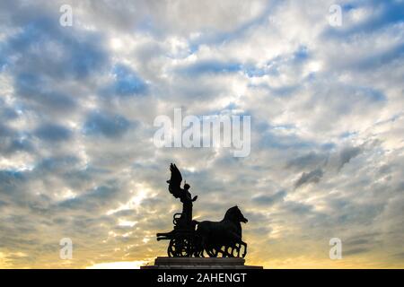 Statue der Göttin Victoria Reiten auf Quadriga auf der Oberseite der Denkmal für Vittorio Emanuele II bei Sonnenuntergang in Rom, Italien. Stockfoto