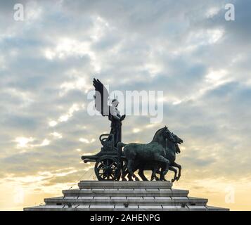 Statue der Göttin Victoria Reiten auf Quadriga auf der Oberseite der Denkmal für Vittorio Emanuele II bei Sonnenuntergang in Rom, Italien. Stockfoto