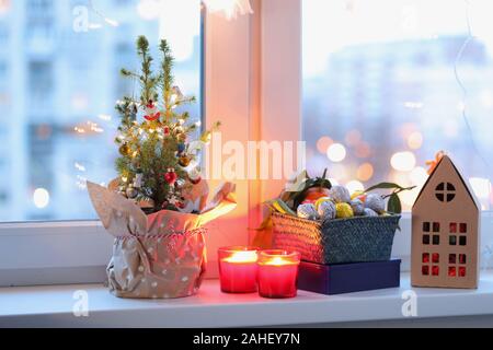 Weihnachtsbaum, Weihnachtsschmuck, Kerzen und Weihnachten Geschenke auf dem Fensterbrett Stockfoto