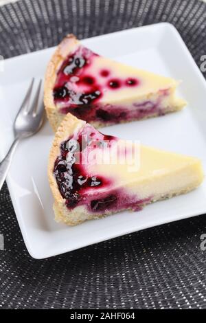 Two slices of black currant cheesecake on a white rectangular plate Stockfoto