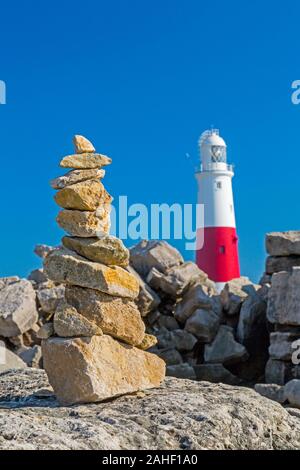 Ein Haufen von balancing Steine und der Leuchtturm von Portland Bill, Dorset, England, Großbritannien Stockfoto