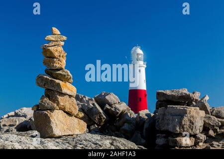 Ein Haufen von balancing Steine und der Leuchtturm von Portland Bill, Dorset, England, Großbritannien Stockfoto