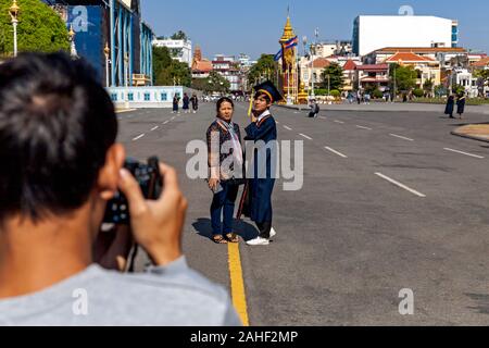 Eine junge männliche Absolvent der Mengly J Quach Bildung steht mit einer Frau, während ein Fotograf ihr Foto in Phnom Penh, Kambodscha. Stockfoto