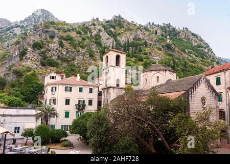 Trg od Drva (Holz), St. Mary's Stiftskirche und die Befestigungen auf die Berge hinter Kotor, Montenegro. Leer in den frühen Morgenstunden Stockfoto