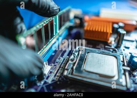 Ingenieur Mechaniker Hände halten in schwarz Handschuhe RAM-Speicher in die Buchse am Computer Motherboard zu stecken. Das Konzept der Technologie Hardware Stockfoto