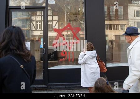Antisemitischen Schmierereien, die in Form von Zahlen, 9, 11, und David Stern, auf ein Schaufenster in Belsize Park, nördlich von London. Stockfoto