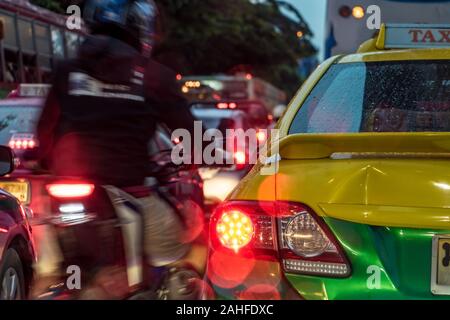 Ein Motorrad überholt ein Queue von Autos in einem Stau. Abend der Verkehr auf den Straßen der Stadt, Bangkok, Thailand. Stockfoto