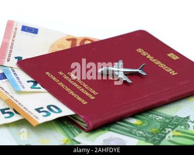 Miniatur Flugzeug auf deutschen Pass mit Euro-banknoten im Inneren auf weißem Hintergrund, kopieren Raum Stockfoto