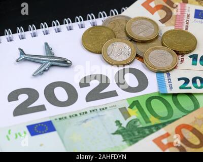 Flugzeug mit Euro-Banknoten und -Münzen, Geld auf Kalender, Konzept des zunehmenden Luftverkehrs im Jahr 2020 Stockfoto