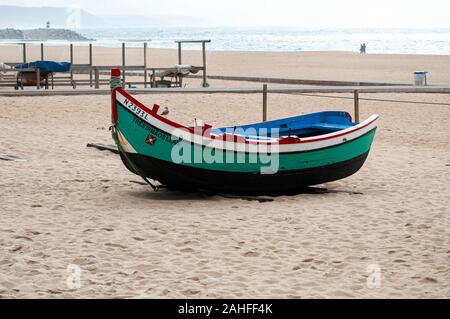 Traditionelle grüne und schwarze Holz- Portugiesische Fischerboot auf den Strand von Nazare, Portugal. Diese Boote sind auf dem Display durch die trockenen Fisch Museum Stockfoto