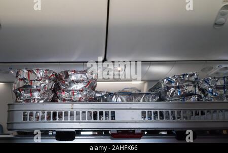 Airline Food oder warme Mahlzeiten in Silberfolie Behältern verpackt auf ein Lebensmittel Trolley in einem Gang auf ein Flugzeug oder ein Flugzeug während des Fluges Stockfoto