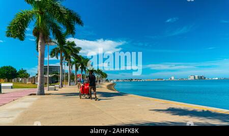 Luanda, angolanischer Zeit - 15. Dezember 2019: Menschen, die an einem sonnigen Tag in der Bucht von Luanda spazieren gehen. Redaktionelle Illustration. Stockfoto