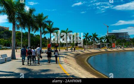 Luanda, angolanischer Zeit - 15. Dezember 2019: Menschen, die an einem sonnigen Tag in der Bucht von Luanda spazieren gehen. Redaktionelle Illustration. Stockfoto