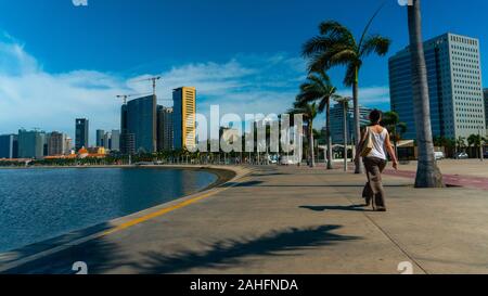 Luanda, angolanischer Zeit - 15. Dezember 2019: Menschen, die an einem sonnigen Tag in der Bucht von Luanda spazieren gehen. Redaktionelle Illustration. Stockfoto