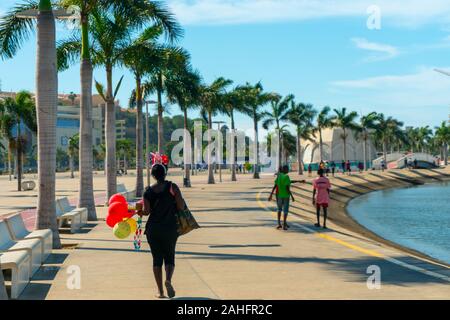 Luanda, angolanischer Zeit - 15. Dezember 2019: Menschen, die an einem sonnigen Tag in der Bucht von Luanda spazieren gehen. Redaktionelle Illustration. Stockfoto