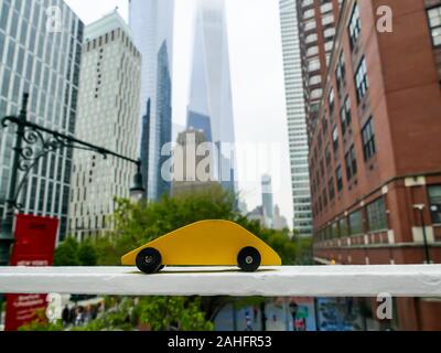 NEW YORK, NY - 03. 2019: Gelb Holzspielzeug auto Blick von der Brücke in der Nähe von Manhattan Gemeinschaft Colege mit One World Trade Center und andere b Stockfoto