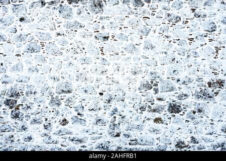 Snowy Oberfläche der Steinmauer. Alten Steinmauer im Schnee Muster Textur Hintergrund. Alte Mauer der antiken Architektur. Hintergrund der alten Steinmauer. Textur der alten Ziegel. Die römische Architektur Stockfoto