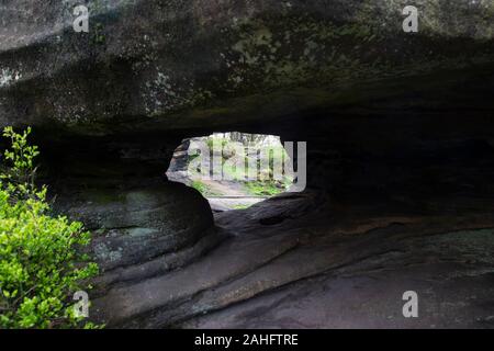 Blick durch eine natürlich entstandene Loch durch Verwitterung in einem Felsen, Eis und Wind an Brimham Rocks, North Yorkshire, England, Großbritannien Stockfoto