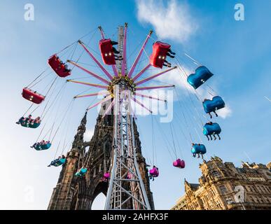 Die Princes Street Gardens, Edinburgh, Schottland, Vereinigtes Königreich. 29. Dezember 2019. Weihnachten feiern: Sonnenschein im Zentrum der Stadt mit der Star Flyer messe Fahrt weg in den Himmel neben dem Scott Monument Stockfoto