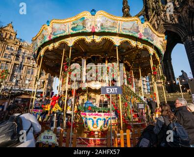 Die Princes Street Gardens, Edinburgh, Schottland, Vereinigtes Königreich. 29. Dezember 2019. Weihnachten feiern: Sonnenschein im Zentrum der Stadt mit Kindern geniessen eine Messe Fahrt auf ein altmodisches Karussell oder Merry-go-round Stockfoto