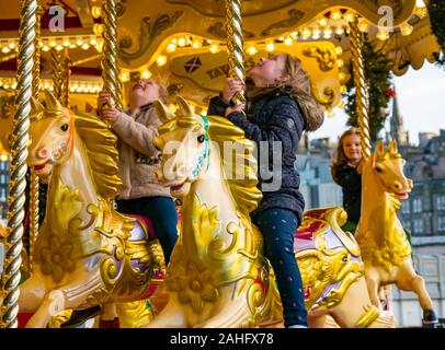 Die Princes Street Gardens, Edinburgh, Schottland, Vereinigtes Königreich. 29. Dezember 2019. Weihnachten feiern: Sonnenschein im Zentrum der Stadt mit Kindern geniessen eine Messe Fahrt auf ein altmodisches Karussell oder Merry-go-round Stockfoto