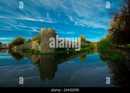 Der berühmte Bischof Palace an der Brunnen in Somerset an einem sonnigen Herbsttag im Oktober 2019. Von einem Wassergraben mit dem Himmel im Wasser umgeben. Stockfoto