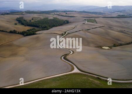 Luftaufnahme von einer ländlichen Landschaft bei Sonnenuntergang in der Toskana. Ländlichen Bauernhof, Zypressen, grüne Felder, Sonne und Wolken. Italien, Europa. Stockfoto