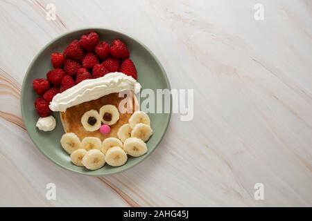 Weihnachten Santa Pfannkuchen mit Himbeeren und Banane für Kinder Frühstück, Ansicht von oben mit der Kopie Platz für Text. Stockfoto