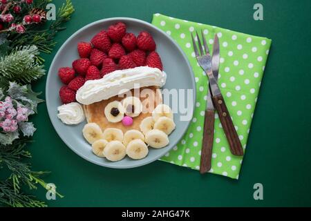 Spaß Essen für Kinder. Weihnachten Santa Pfannkuchen mit Himbeeren und Banane für Kinder Menü, Ansicht von oben mit der Kopie Platz für Text. Stockfoto