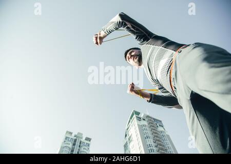 Ansicht von unten auf das bärtige Sportler Suchen in die Ferne während des Trainings Stockfoto