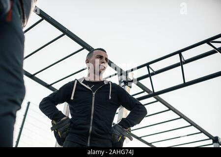 Taille bis schwerer Sportler seine Hände auf die Hüften und Denken Stockfoto