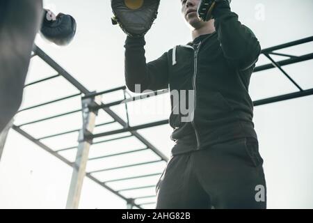 In der Nähe von schweren Trainer tragen focus Mitts und suchen ernsthafte Stockfoto