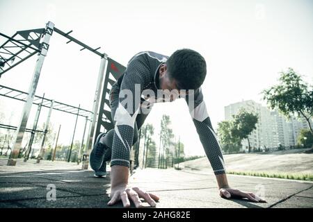 Ruhe Sportler immer bereit für den Betrieb und die Hände auf den Boden Stockfoto