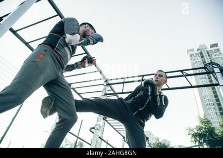 Ernsthafte MMA Boxer tun Punsch mit seinem Bein während des Trainings Stockfoto