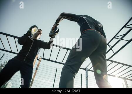Ansicht von unten auf das ruhige Mann, der focus Mitts während der boxtraining Stockfoto