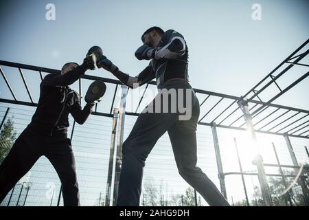 Ansicht von unten auf das MMA Boxer immer bereit für den Wettbewerb mit seinem Trainer Stockfoto