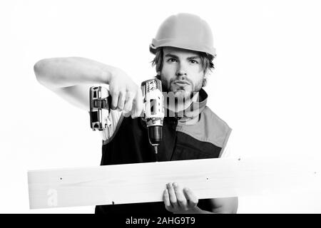 Mann mit Konzentriertem Gesicht, auf weißem Hintergrund. Builder in orange Helm und Uniform. Work in progress und Gebäudekonzept. Reparatur der Arbeitnehmer nutzt gelb Bohrung in Holzbrett zu machen Stockfoto