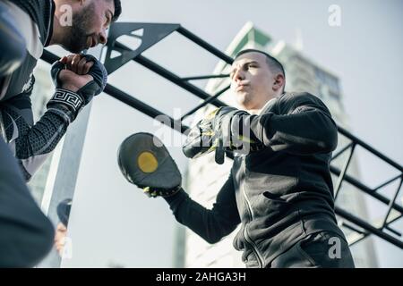 Nahaufnahme von ernster Mann mit Schwerpunkt Fausthandschuhe und der Boxer Schläge tun Stockfoto