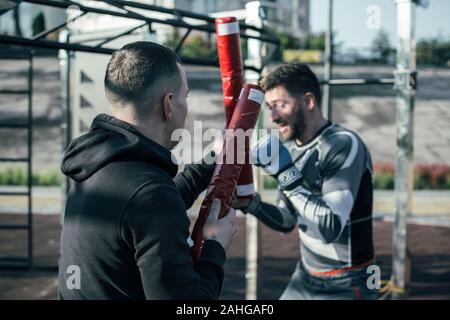 Der junge Mann mit Boxing Stick und der Boxer immer bereit Stockfoto