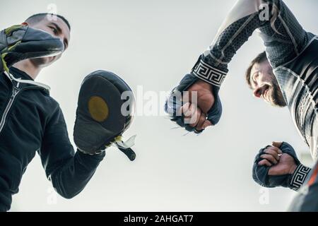 Nahaufnahme von professionellen Trainer mit Schwerpunkt Fausthandschuhe helfen MMA Boxer Stockfoto