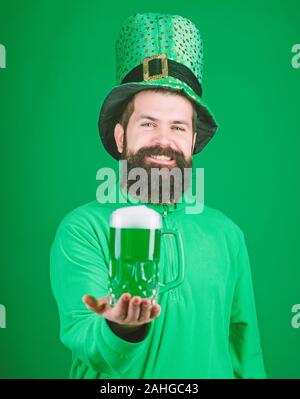 Frisch gezapftes Bier. Hipster in grünen Kobold hat Holding Bierkrug. Irische Mann mit Bart trinken grünen Bier. Feiern Saint Patricks Day in bar an. Bärtiger Mann Toasten zu Saint Patricks Day. Stockfoto