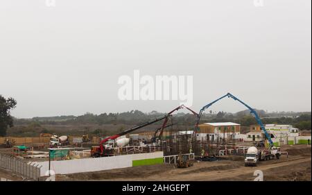 Wohnungsbau-Baustelle mit Lastwagen, Arbeitern und Kränen am bewölkten Tag in La Serena, Chile Stockfoto