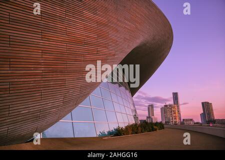 Queen Elizabeth Olympic Park, London, 29. Dezember 2019. Wie ein riesiges Auge, das London Aquatics Center (Design von Architektin Zaha Hadid) erscheint "Peek" an der sanften Pastelltönen Licht der Winter Sonnenuntergang in London, nach einer weitgehend klaren, sonnigen Tag in der Hauptstadt. Credit: Imageplotter/Alamy leben Nachrichten Stockfoto