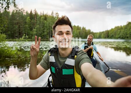 Zwei Männer im Leben haben Kanufahren im Waldsee. Wasseroberfläche mit Seerosen bedeckt. Touristen, die in Finnland reisen und Abenteuer erleben. Freunde Takin Stockfoto